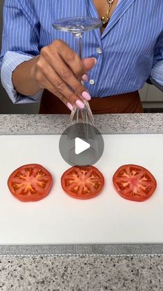 a woman holding a wine glass in front of four tomatoes