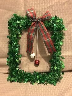 a christmas wreath made out of green tinsel with a red and white ornament