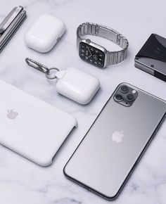 an assortment of electronics and accessories laid out on a marble counter top, including an apple watch