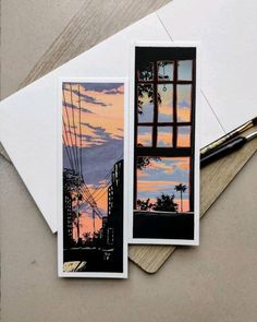 two cards with an image of a city at sunset and a pen on the table