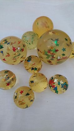 some glass balls are sitting on a white tablecloth and one is yellow with stars