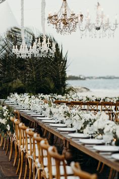 a long table with white flowers and greenery is set up for an outdoor wedding