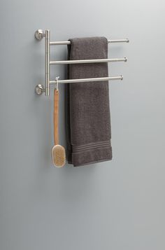 a towel rack with two towels and a brush hanging from it's side on the wall