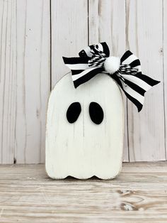 a white pumpkin with a black and white bow on it sitting in front of a wooden wall