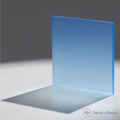 a blue glass block sitting on top of a white table next to a gray wall