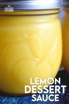 two jars filled with lemon dessert sauce sitting on top of a blue cloth covered table