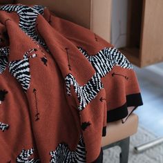 an orange and black blanket sitting on top of a chair next to a wooden table