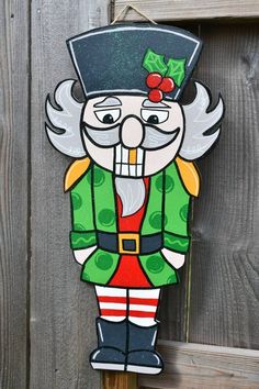 a wooden sign with an image of a santa clause wearing a green hat and red pants