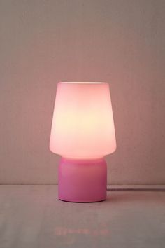 a pink table lamp sitting on top of a white floor next to a gray wall