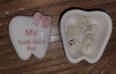 two tooth shaped dishes with pink bows on them sitting on a wooden table next to each other