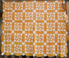 an orange and white quilt hanging on a fence