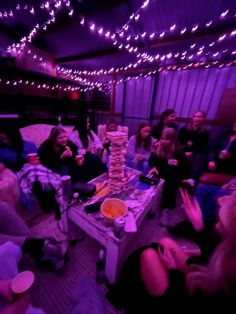 a group of people sitting around a table in a room with purple lights on the ceiling