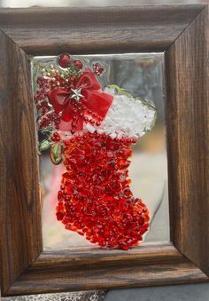 a christmas stocking made out of glass in a frame with red and white beads