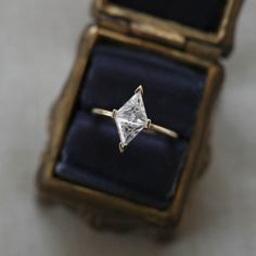 an engagement ring with a princess cut diamond sits in a box on a table top