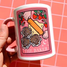 a hand holding a coffee mug with the words the baker on it and strawberries