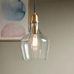 a clear glass light hanging from a ceiling fixture in a room with a painting on the wall