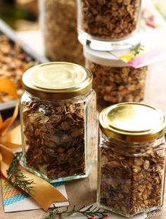 three glass jars filled with granola sitting on top of a table next to ribbon