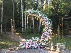 an outdoor wedding setup with flowers and candles on the ground, surrounded by birch trees