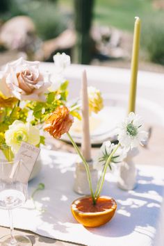 an arrangement of flowers and candles on a table