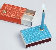 a small matchbox with a lit candle in it next to an open matches box