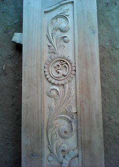 an intricately carved wooden door on the side of a building, with flowers and leaves