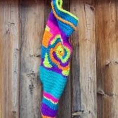 a colorful crocheted umbrella hanging on a wooden fence