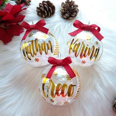 three christmas ornaments with red bows on them and pine cones in the background, all decorated by hand