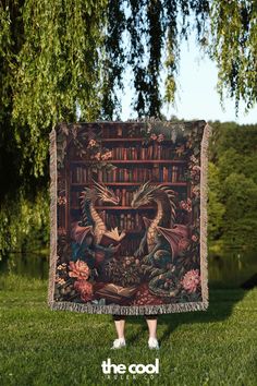 a woman standing in front of a book shelf with a dragon tapestry on it