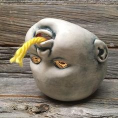 a ceramic head with yellow eyes and a string attached to it's nose, sitting on a wooden surface