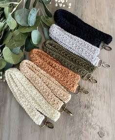 four crocheted headbands are lined up on a wooden surface next to flowers