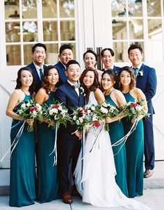 a group of people standing next to each other in front of a white door wearing green dresses