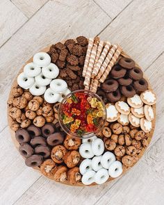 a wooden platter filled with lots of different types of donuts and pretzels