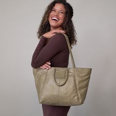 This bag has everything you want in a tote top zip closure, a padded tech pocket, solid leather straps, and Sheilas signature circular handles that fold down when not in use Sheila EastWest Tote In Metallic Leather  Burnished Sage TOTE Bag in Sage Green | Hobo® Modern Weekender Bag For Everyday Use, Modern Travel Satchel With Rolled Handles, Everyday Satchel With Rolled Round Handles, Versatile Travel Satchel With Round Handle, Modern Everyday Shoulder Bag With Handles, Everyday Shoulder Bag With Removable Pouch And Round Handle, Modern Satchel With Rolled Handles For Daily Use, Shoulder Bag With Rolled Handles For Everyday, Modern Weekender Bag With Detachable Handle For Daily Use