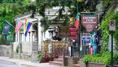 a row of houses with flags on the street and trees in front of them,