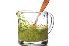 a glass pitcher filled with green liquid and a wooden spoon