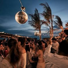 a group of people standing next to each other at a party with disco balls hanging from the ceiling