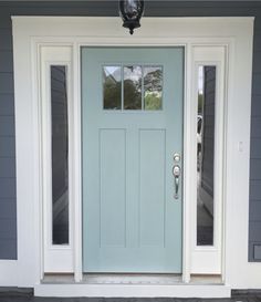 a blue front door with two sidelights and a light fixture on the outside wall