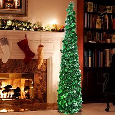 a green christmas tree sitting in front of a fire place