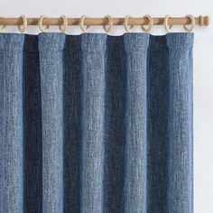 a blue curtain hanging on the side of a window with wooden hooks in front of it