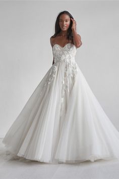 a woman in a wedding dress posing for the camera with her hand on her head