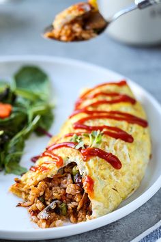 an omelet with meat and vegetables on a white plate next to a salad