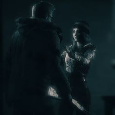 two people standing next to each other in the dark with one person holding a knife