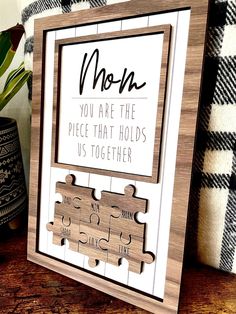 a wooden frame with puzzle pieces on it that says mom you are the piece that holds us together