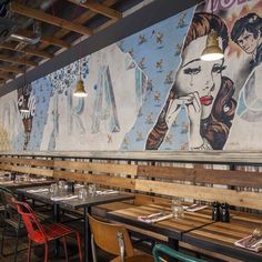 an empty restaurant with tables and chairs in front of a mural on the back wall