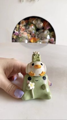 a hand is holding a small green figurine