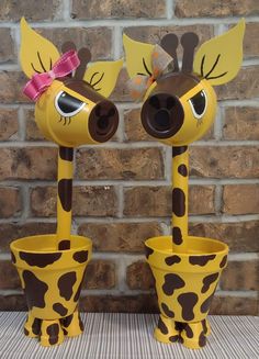 two giraffe shaped planters sitting on top of a table next to a brick wall