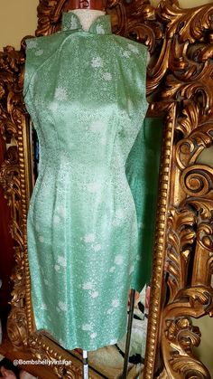 This beautiful Asian style dress is from the 60's. Pristine condition.  Made of a soft green chrysanthemum brocade with touches of gold. Fitted cheongsam style. Side nylon zipper. Closes with snaps across the upper bust. Lined in a deeper green fabric.  Best fit would be a Small, however, please see the measurements below for a proper fit.  All sales are final. Measurements Armpit-armpit doubled 35" Wasit 26" HIp 35" Length 37"135 Green Brocade Party Dresses, Green Brocade Dress For Formal Occasions, Formal Green Brocade Dress, Green Brocade Formal Dress, Festive Green Brocade Dress, Elegant Green Festive Ao Dai, Festive Fitted Green Ao Dai, Vintage Brocade Fitted Dress, Fitted Vintage Brocade Dress