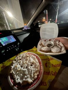 a person holding a plate of food in their hand next to a box of doughnuts