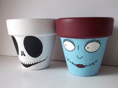 two pots with faces painted on them sitting next to each other, one is blue and the other is red