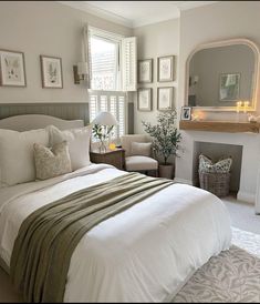 a bedroom with a white bed, fireplace and pictures on the wall above it's headboard